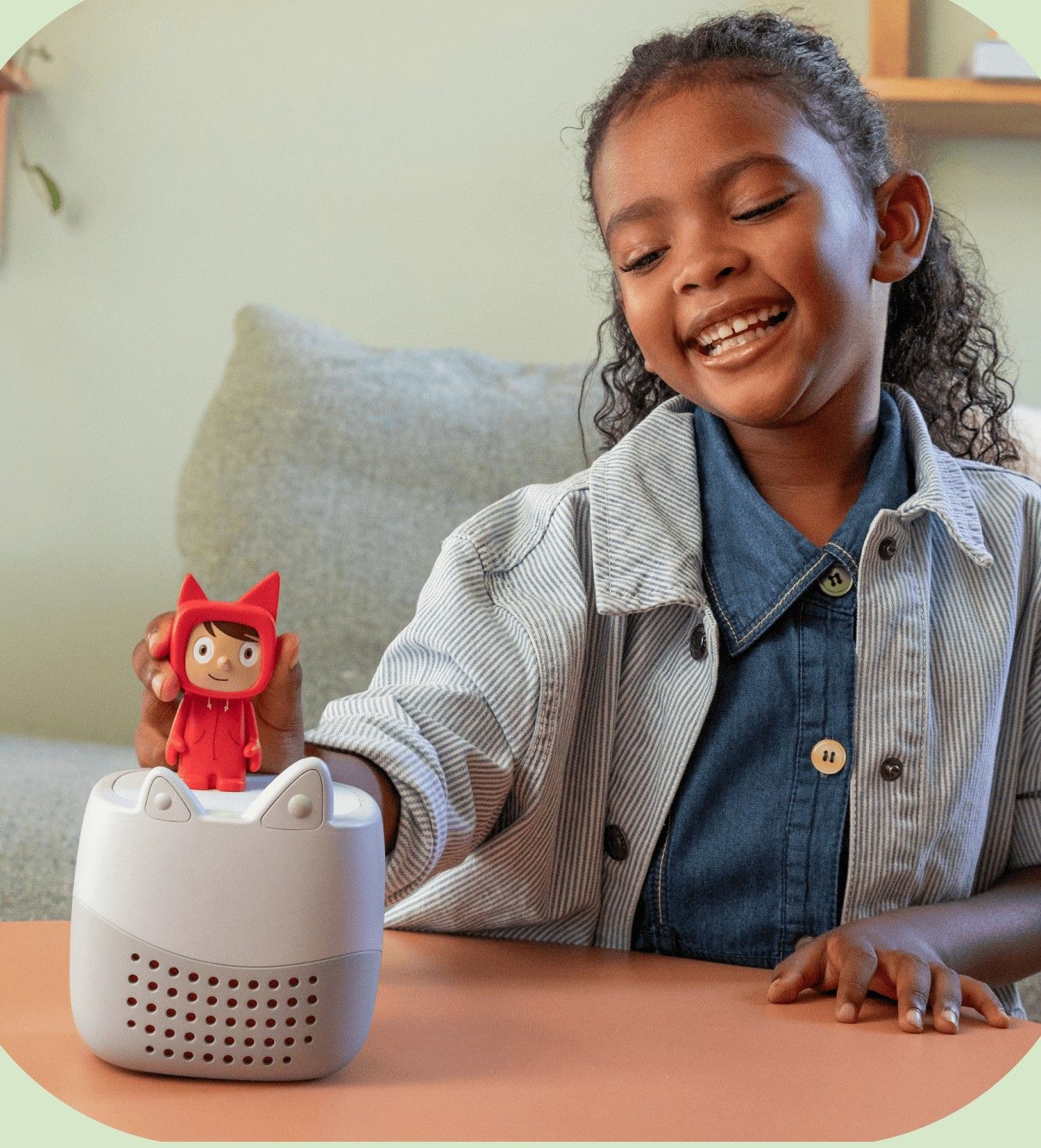 A girl smiling as she places a Tonie figure on her Toniebox
